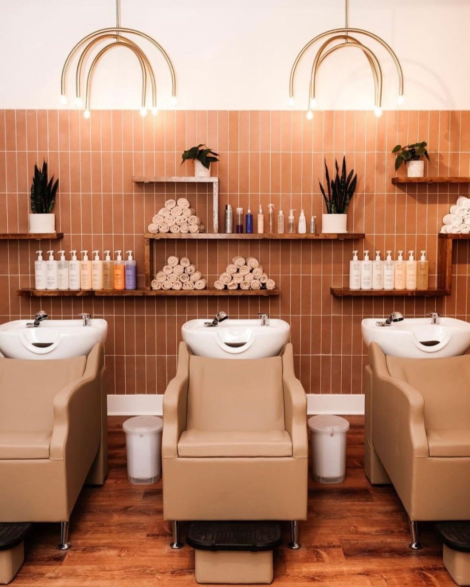 salon supplies organized on wall-mounted shelves in the shampoo area