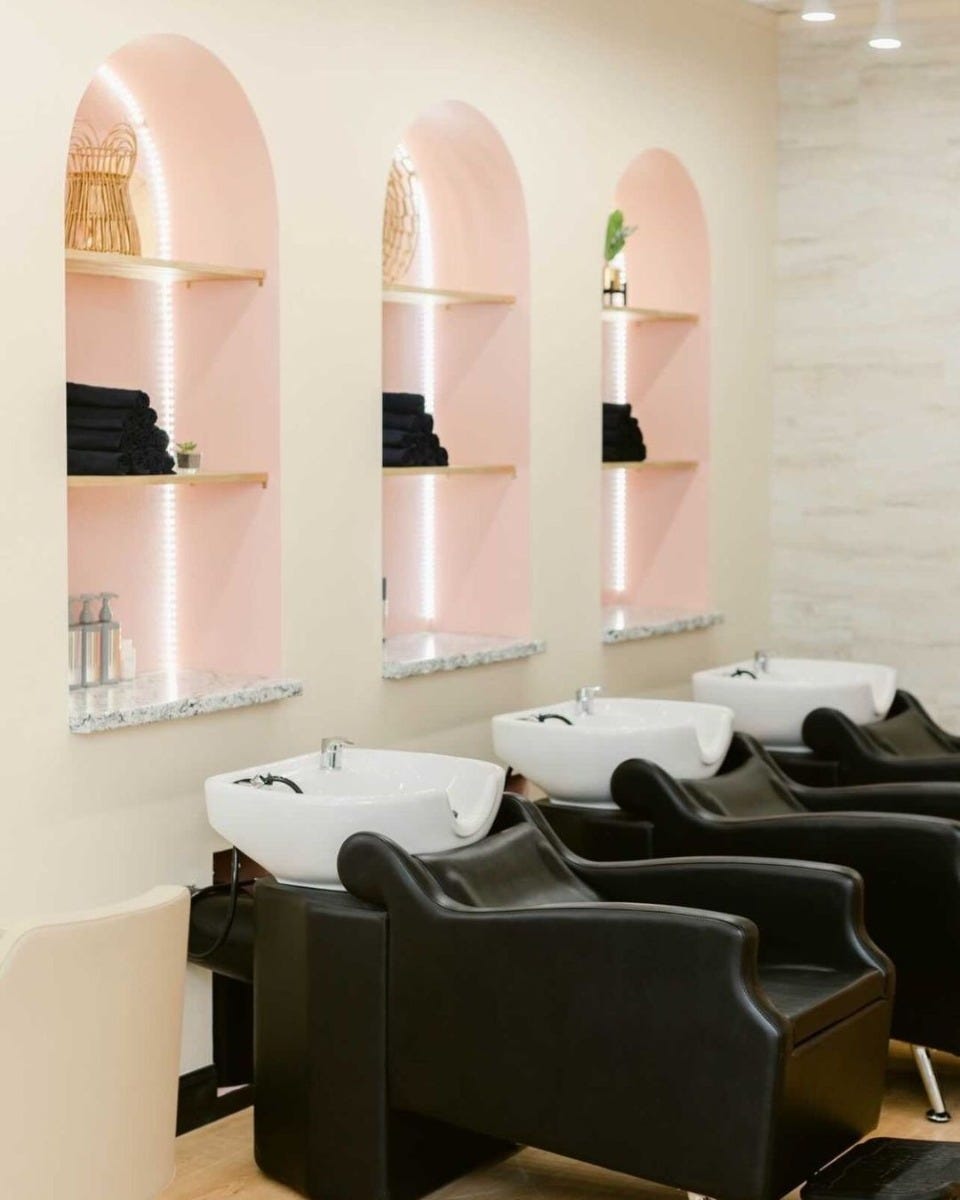 arched lighted salon retail shelves with pink accent color and black backwash units