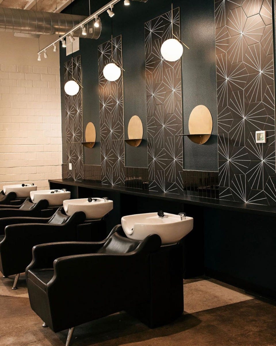 salon shampoo area with mid century modern wall tiles, pendant lights and circular wall shelves