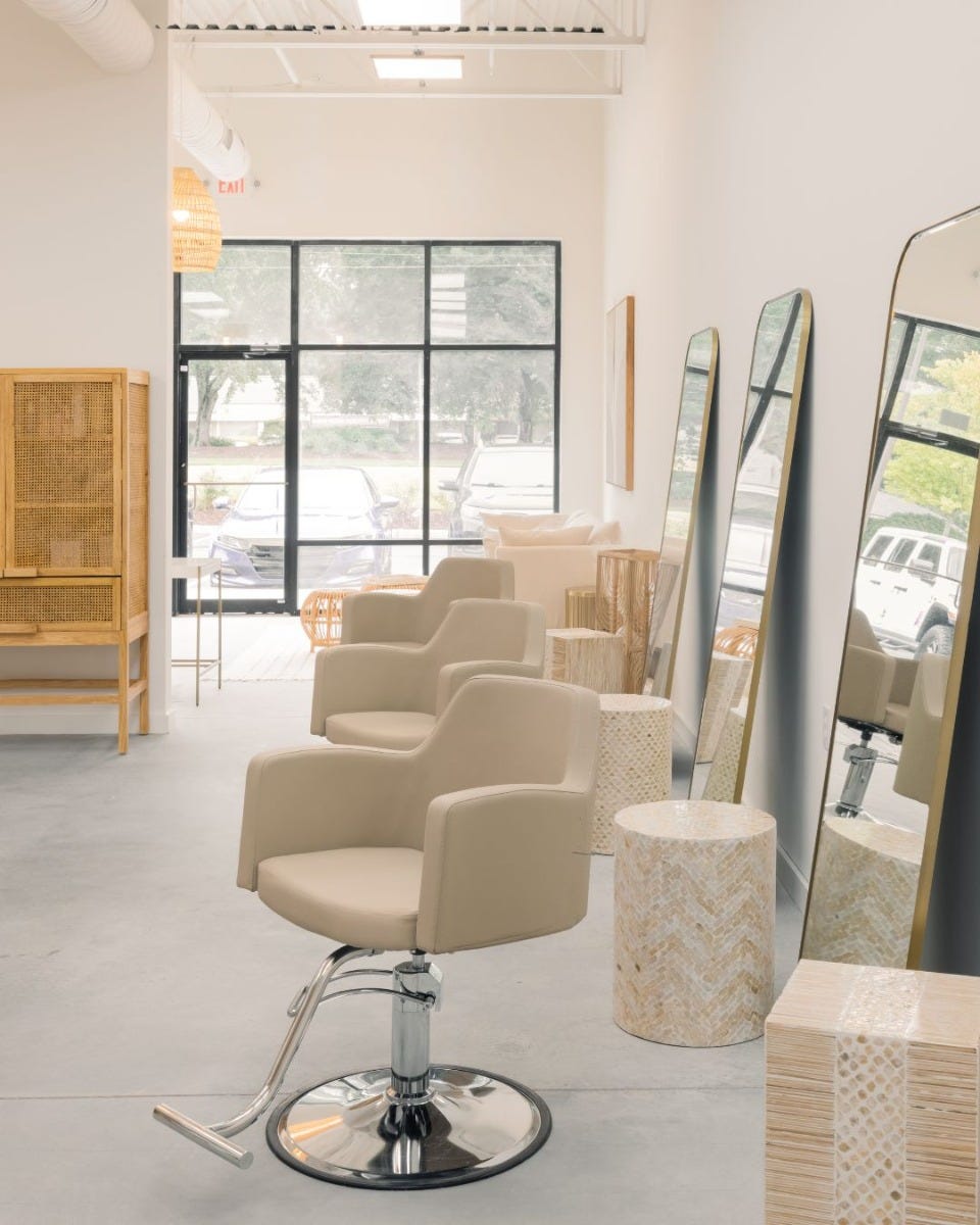 salon stations with five and a half feet of space between them arranged along the wall in a small, bright and airy hair salon