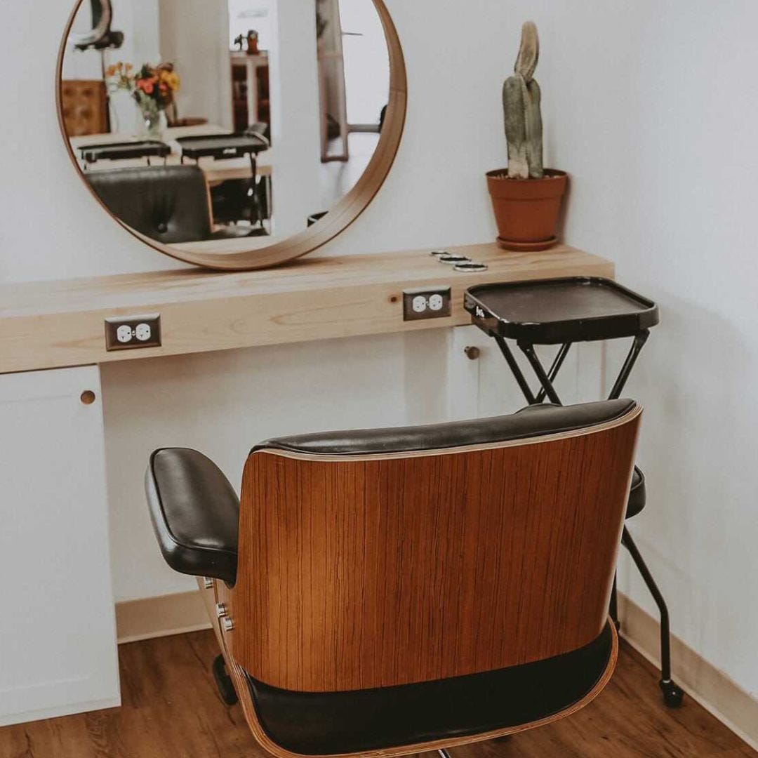 salon station with mobile black folding service tray, black leather and wood grain styling chair and round mirror