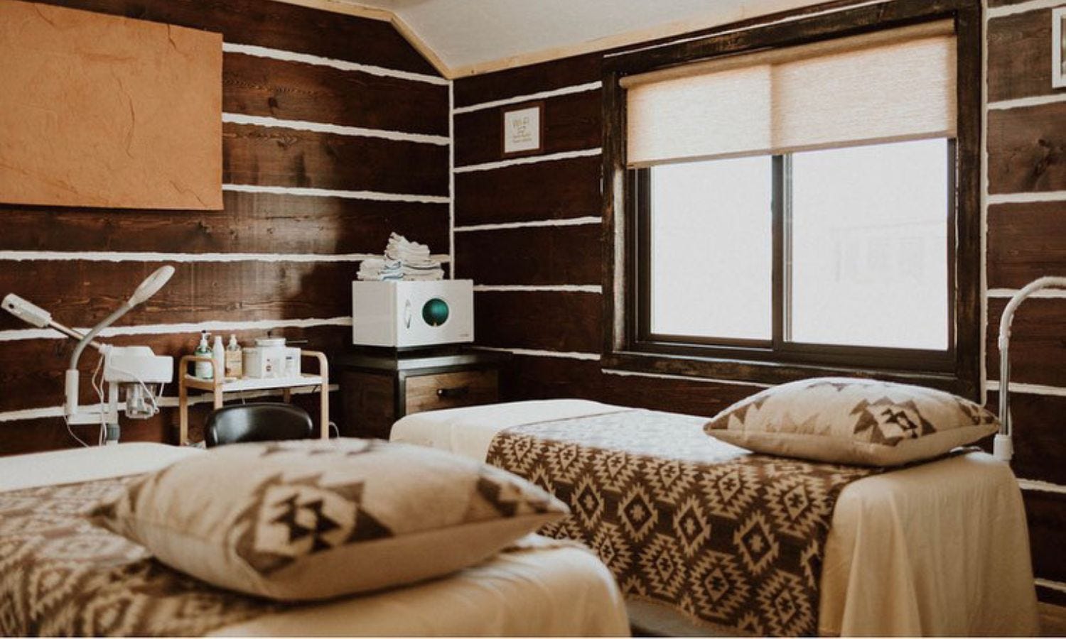 spa treatement room with facial beds, mag lamps, towel warmer and supply storage cabinet