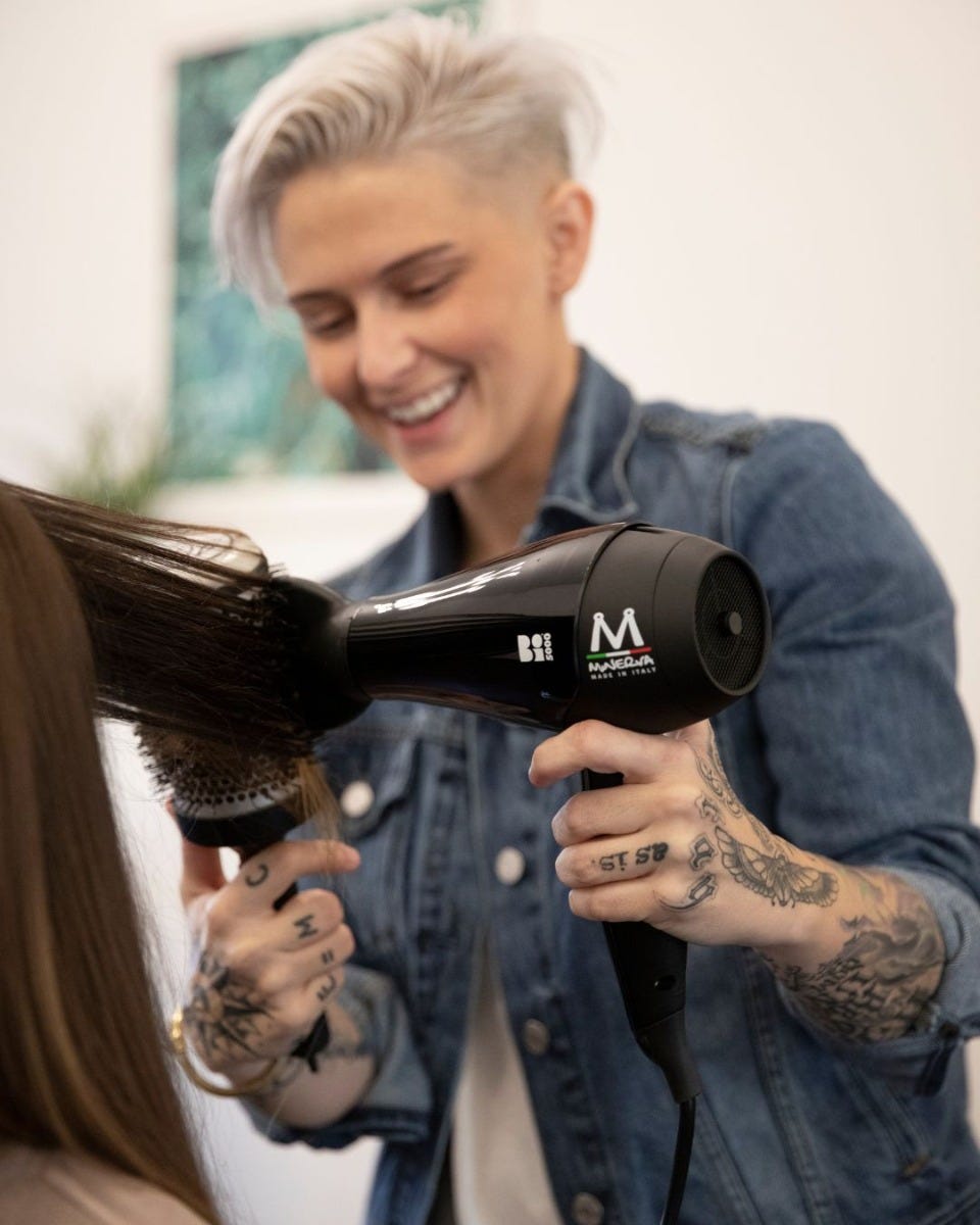 professional stylist drying a client’s hair using a Minerva Beauty hair dryer and round brush