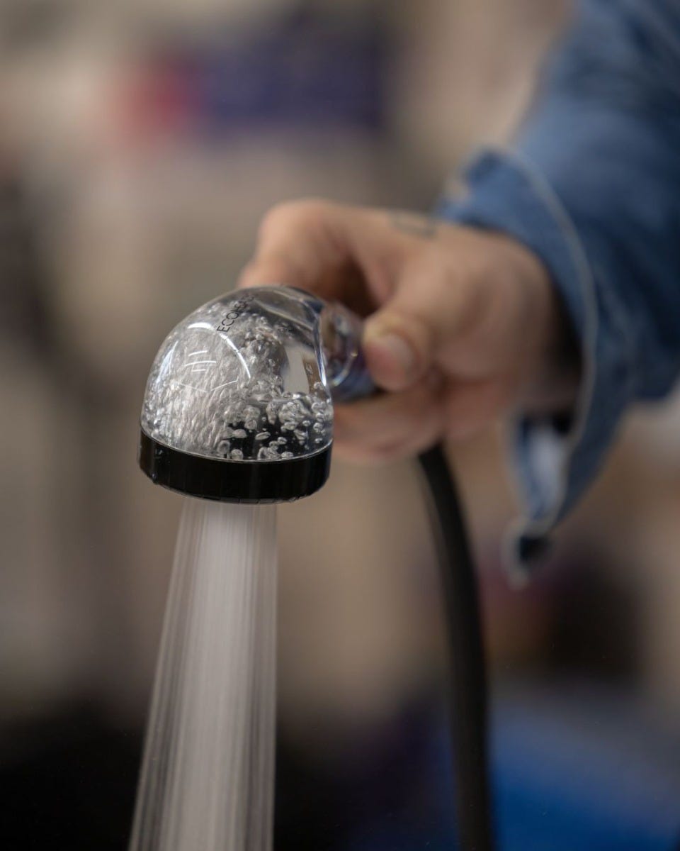 hair stylist demonstrating water pressure of eco-friendly shampoo sprayer