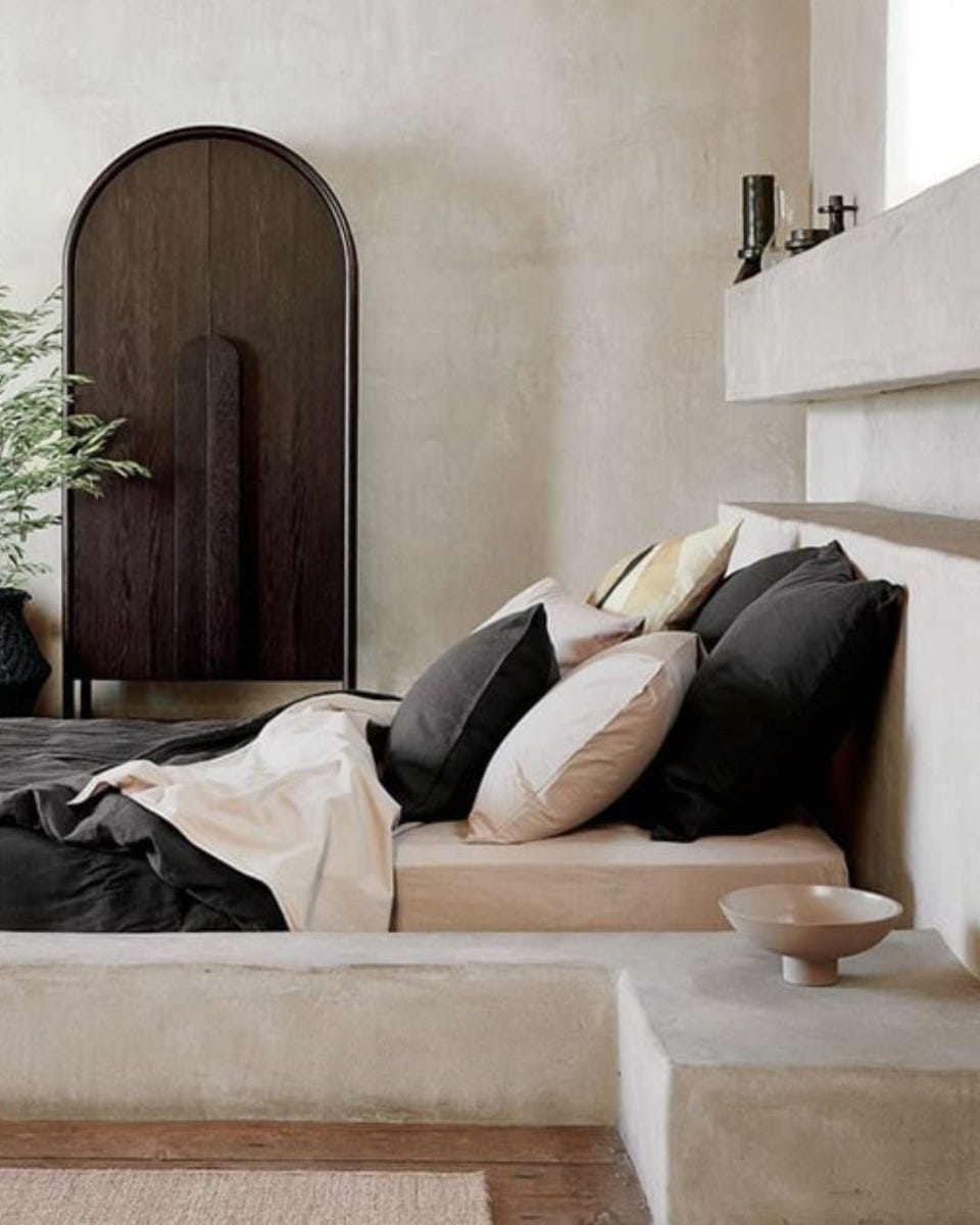 minimalist bedroom with black and white bedding and built-in shelving around bed