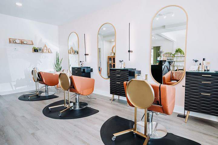 luxury hair salon styling stations with chairs, service trays and oval mirrors