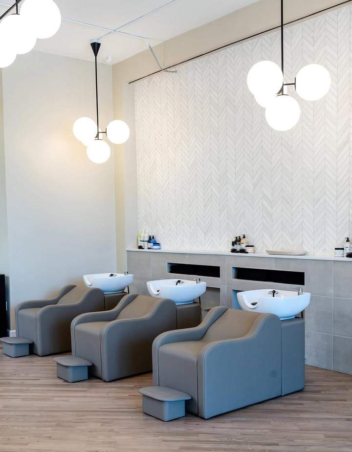 small salon suite shampoo area with natural light, wood flooring, plants and single backwash unit