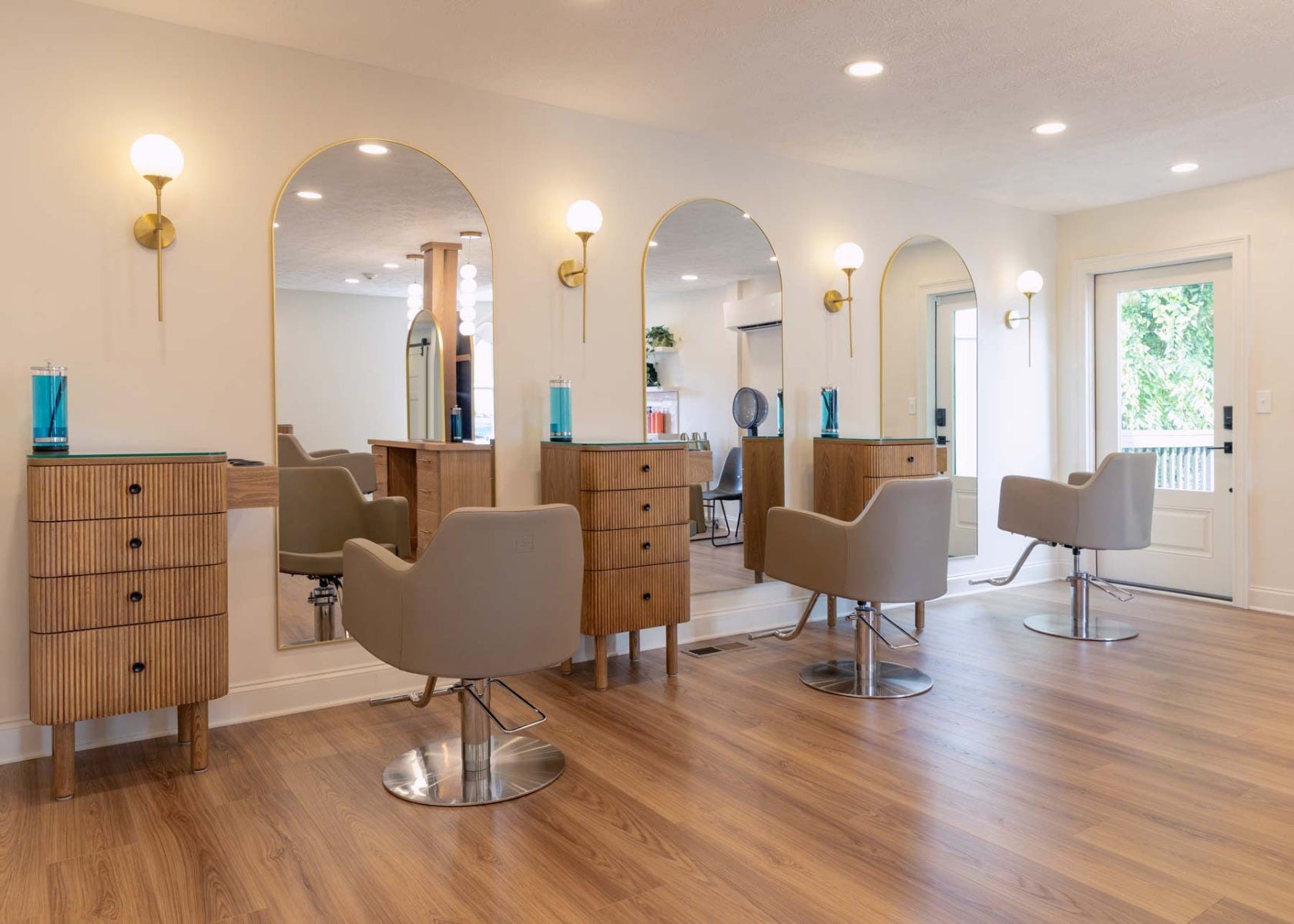 J. Italia Salon interior view of three salon stations outfitted with styling chairs, storage and arched mirrors