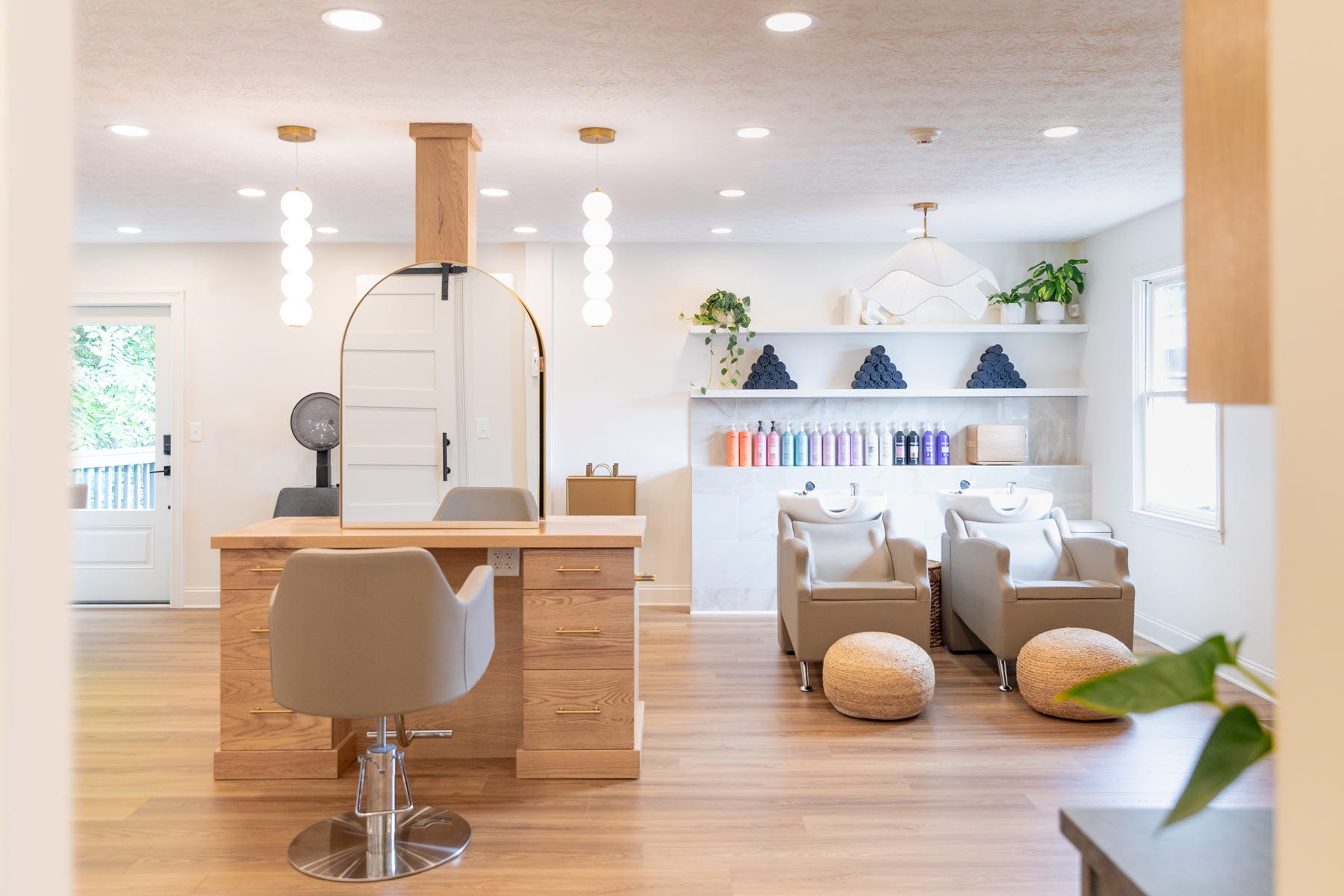 J. Italia Salon interior view of double-sided styling station and shampoo area with two shampoo systems and shelving