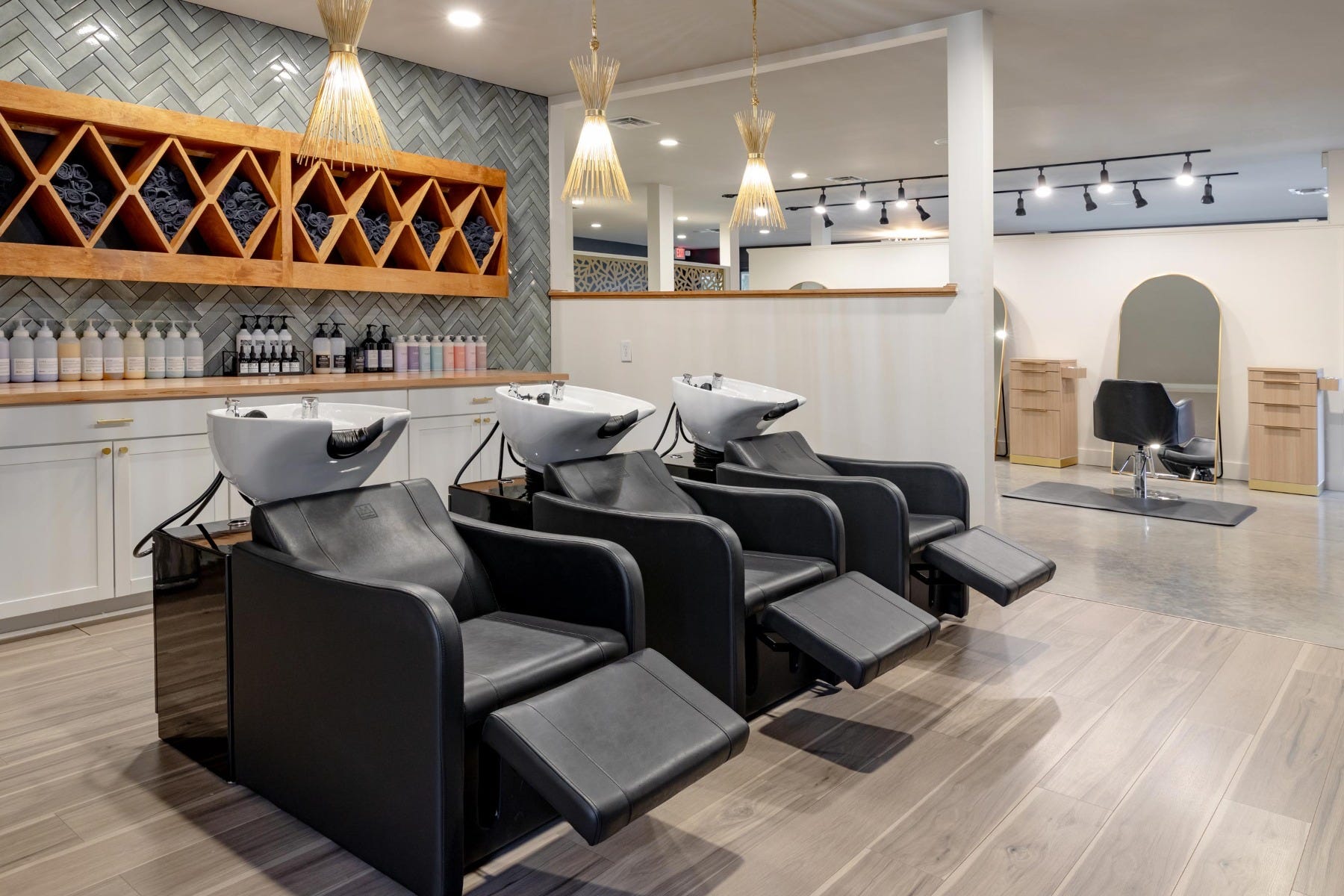 Vibe Salon alternate interior view of shampoo area with shampoo stations in reclined position and styling stations visible in background