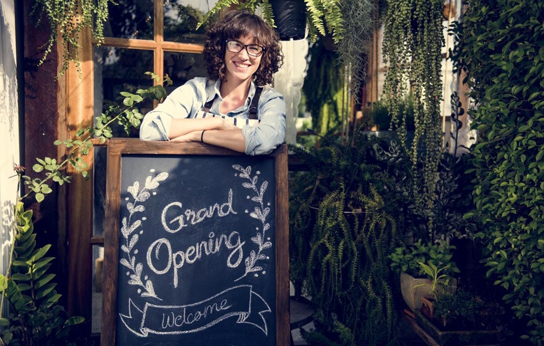 woman standing with grand opening sign